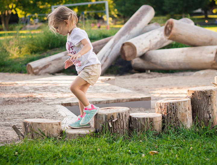Child playing in a play area situated in open green space